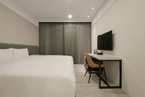 a hotel room with a bed and a desk at Fengjia JinRui Hotel in Taichung