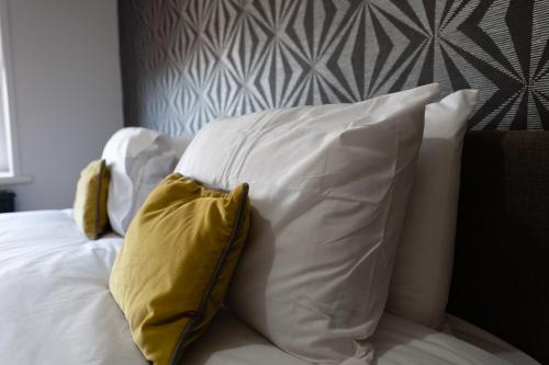 a pile of pillows sitting on top of a bed at 5 Bed Workington House with Parking Near Station in Workington