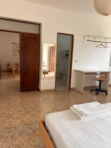 a bedroom with a bed and a desk and a mirror at Tarrafal Ecodécor Rooms in Tarrafal