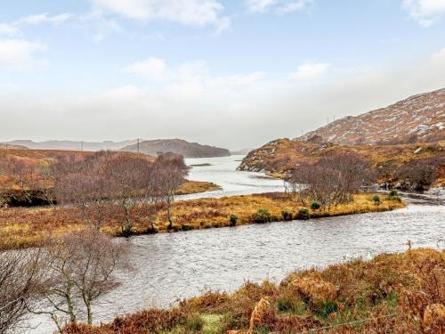 a river in a field with mountains in the background at 6 Bed in Lairg CA210 in Achlyness