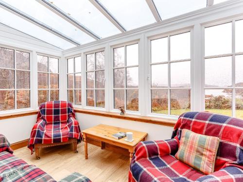 two chairs and a table in a room with windows at 6 Bed in Lairg CA210 in Achlyness