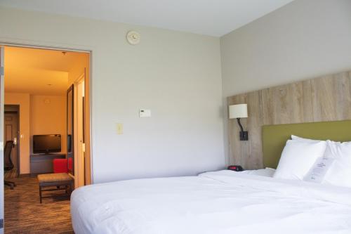 a bedroom with a large white bed and a living room at Country Inn & Suites by Radisson, Carlisle, PA in Carlisle