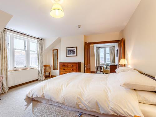 a bedroom with a large bed and two windows at 6 Bed in Lairg CA210 in Achlyness