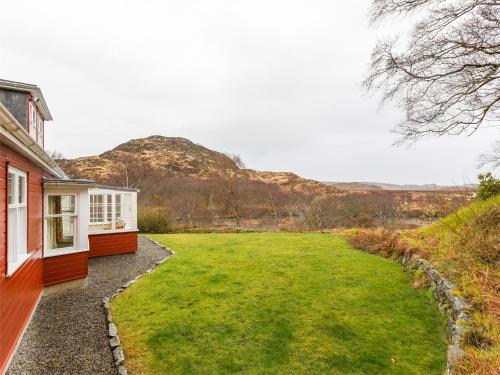 a house with a large yard next to a mountain at 6 Bed in Lairg CA210 in Achlyness