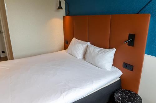 a bed with white pillows and an orange headboard at ibis Lyon Est Bron in Bron
