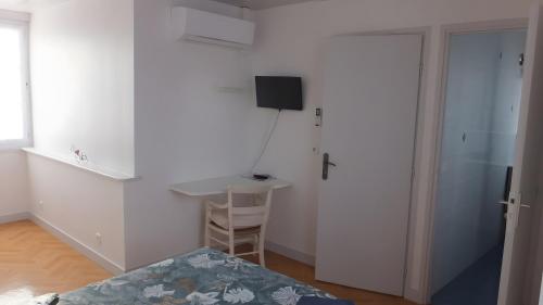 a room with a bed and a desk and a television at Chambres d’hôtes Chantal Hereaudeau in Les Moulins de la Boire