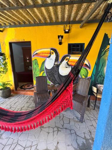 two birds sitting on a hammock in front of a building at Pousada Recanto do Tucano in Cavalcante