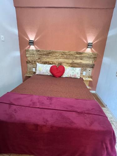 a bed with a red heart pillow on it at Pousada Recanto do Tucano in Cavalcante
