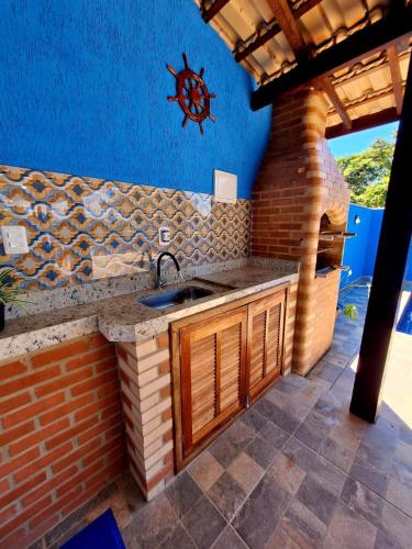 a kitchen with a sink and a brick wall at La casa Azul- Búzios in Búzios