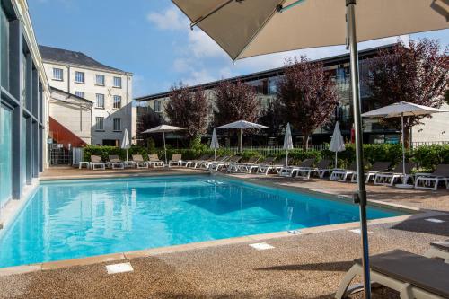 ein großer Pool mit Stühlen und einem Sonnenschirm in der Unterkunft Pierre & Vacances Le Moulin des Cordeliers in Loches