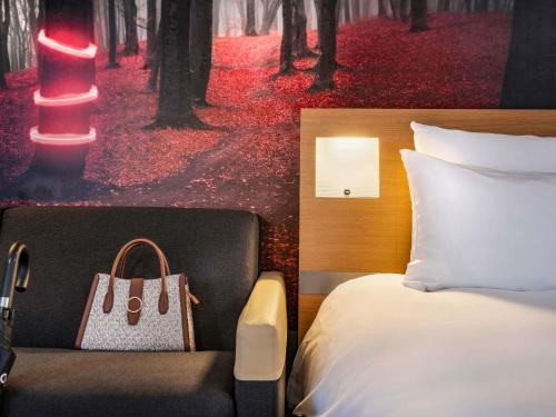 a bedroom with a bed and a chair with a purse at Novotel Paris Est in Bagnolet