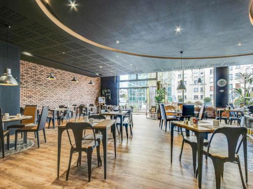 a restaurant with tables and chairs and a brick wall at Novotel Paris Est in Bagnolet