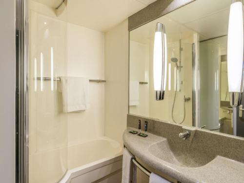 a bathroom with a sink and a shower and a tub at Novotel Paris Créteil Le Lac in Créteil