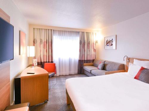 a hotel room with a bed and a couch at Novotel Marne La Vallée Collégien in Collégien