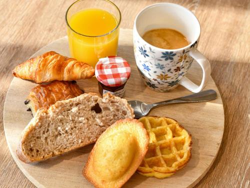 a plate of bread and waffles and a cup of orange juice at Novotel Paris Créteil Le Lac in Créteil