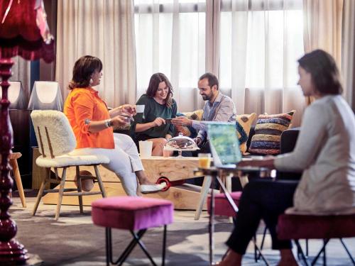 a group of people sitting around a table in a living room at Novotel Marne La Vallée Collégien in Collégien