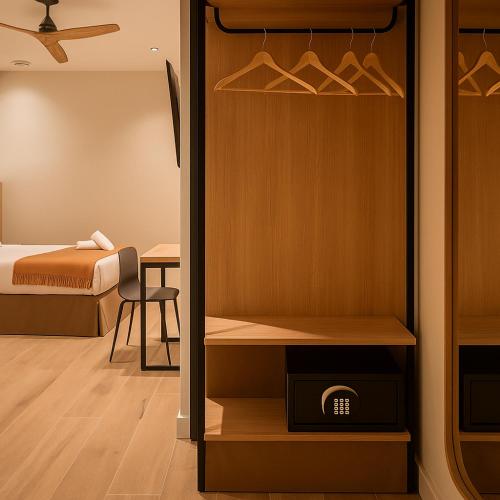 a room with a closet with a bed and a desk at Aerohotel Barcelona Airport 24h in El Prat de Llobregat