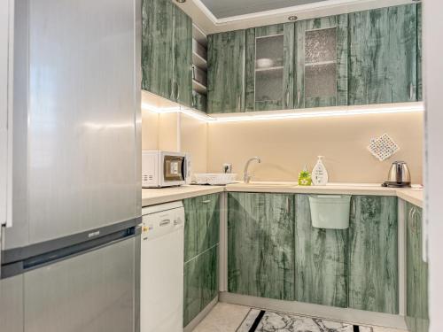a kitchen with green wooden cabinets and a refrigerator at 2BR Vintage Apt next to Tsar Simeon Garden by Flat Manаger in Plovdiv