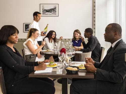 a group of people sitting around a table eating at Mercure Paris Le Bourget Aeroport in Le Blanc-Mesnil