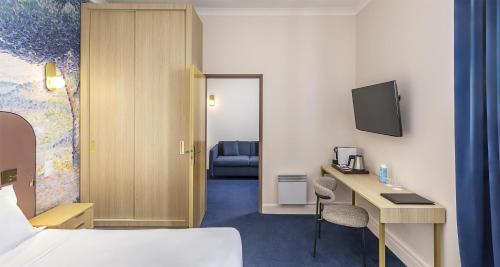 a hotel room with a bed and a desk and a tv at Best Western Poitiers Centre Le Grand Hôtel in Poitiers
