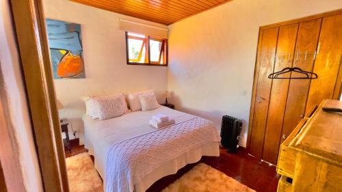 a bedroom with a white bed in a room at Pousada Hortelã in Campos do Jordão