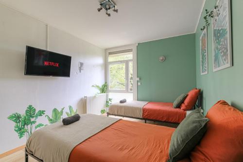 a bedroom with two beds and a tv on the wall at Appartement 2 Chambres - Le Tropical in Oullins
