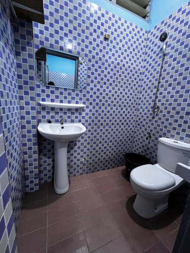 a blue tiled bathroom with a toilet and a sink at Les Résidences de Cobat in Kika
