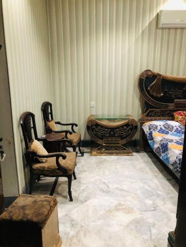 a room with two beds and chairs and a table at 2 Furnished rooms in a house in Faisalabad