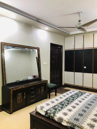 a bedroom with a mirror and a bed and a dresser at 2 Furnished rooms in a house in Faisalabad