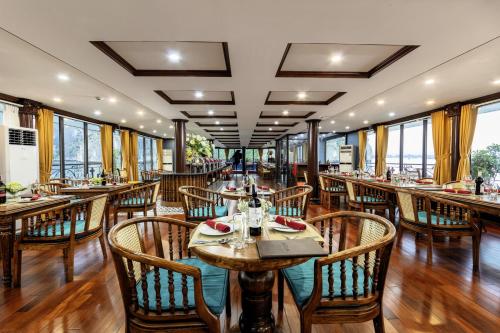 a restaurant with wooden tables and chairs and windows at Verdure Lotus Grandeur Cruise on Ha Long Bay in Ha Long