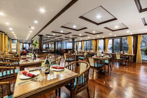 a restaurant with wooden tables and chairs and windows at Verdure Lotus Grandeur Cruise on Ha Long Bay in Ha Long