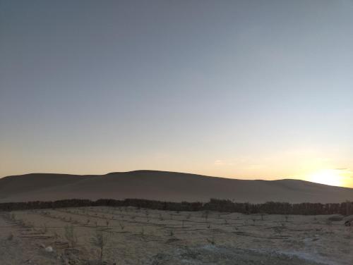 a sunset over a field with mountains in the background at sabrina camp in Siwa