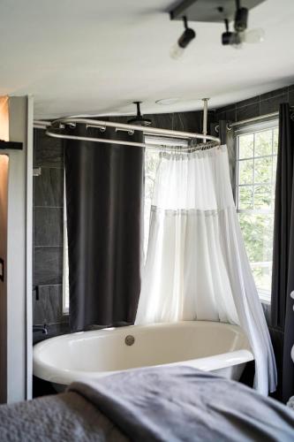 a bathroom with a bath tub and a shower curtain at Sonlit Retreats in Skyline