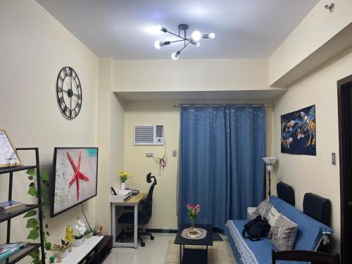 a living room with a blue couch and a clock at 1BR Condotel in Pasay Manila Near NAIA Airport, Mall of Asia, Manila Bay, PICC and CPP Pet-Friendly with Pool, Fast WiFi, Netflix in Manila