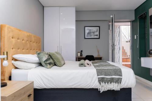 una habitación con una cama grande con sábanas y almohadas blancas en Modern Apartment in Mouille Point with Green Point Park Access, en Ciudad del Cabo