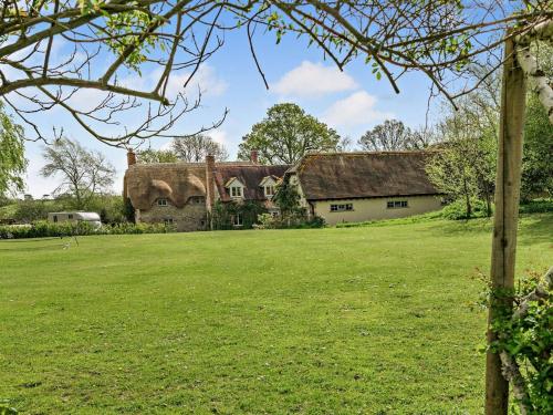 an old house with a thatched roof on a grass field at 5 Bed in Sturminster Newton 76458 in Lydlinch