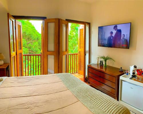 a bedroom with a bed and a tv on the wall at Pousada Hortelã in Campos do Jordão