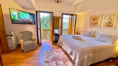 a bedroom with a bed and a tv and a chair at Pousada Hortelã in Campos do Jordão