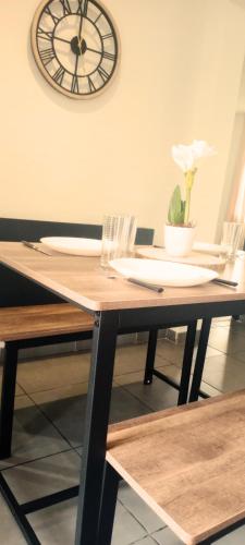 a table with a plate and a clock on the wall at Charmante maison familiale proche Bordeaux in Floirac