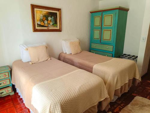 a room with two beds and a blue cabinet at Pousada Hortelã in Campos do Jordão