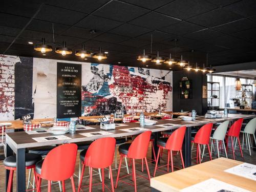 a restaurant with red chairs and tables and a brick wall at Hotel Novotel Evry Courcouronnes in Evry-Courcouronnes