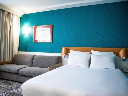 a hotel room with a bed and a couch at Hotel Novotel Evry Courcouronnes in Evry-Courcouronnes