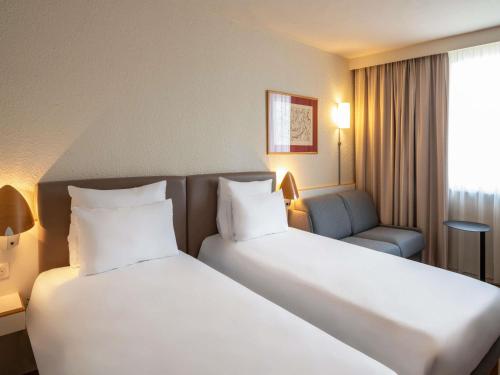 a hotel room with two beds and a couch at Hotel Novotel Evry Courcouronnes in Evry-Courcouronnes