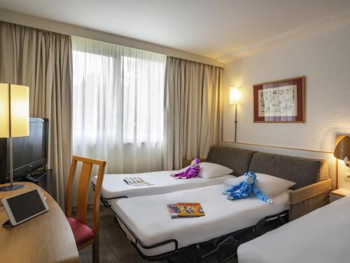 a hotel room with two beds with stuffed animals on them at Hotel Novotel Evry Courcouronnes in Evry-Courcouronnes