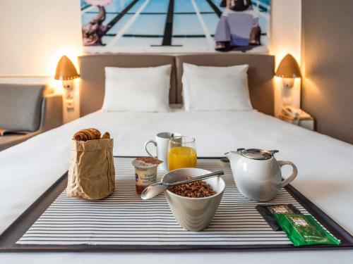 a tray with food and drinks on a bed at Hotel Novotel Evry Courcouronnes in Evry-Courcouronnes