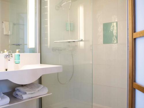 a bathroom with a glass shower and a sink at Hotel Novotel Evry Courcouronnes in Evry-Courcouronnes