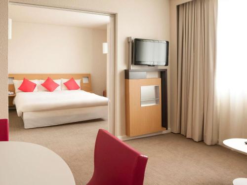 a hotel room with a bed and a tv at Hotel Novotel Evry Courcouronnes in Evry-Courcouronnes