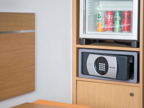 a microwave sitting on top of a cabinet with soda cans at Hotel Novotel Evry Courcouronnes in Evry-Courcouronnes