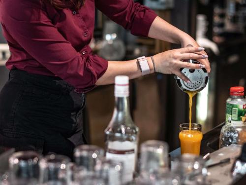 a woman pouring a drink into a glass at Hotel Novotel Evry Courcouronnes in Evry-Courcouronnes