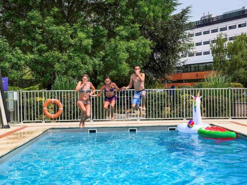 a group of people standing next to a swimming pool at Hotel Novotel Evry Courcouronnes in Evry-Courcouronnes